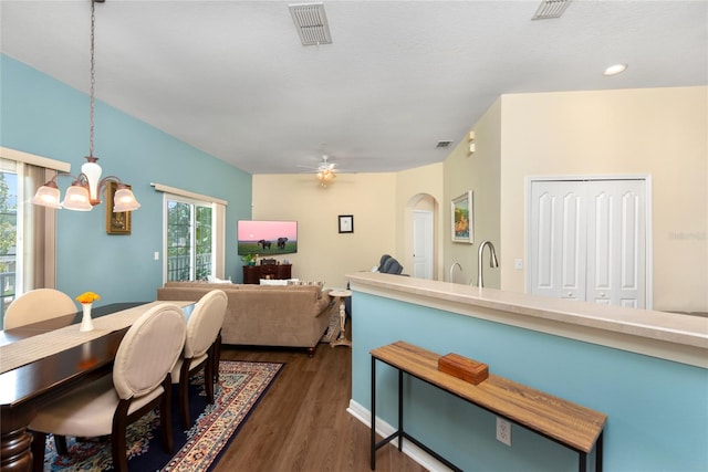 dining space featuring ceiling fan with notable chandelier and dark wood-type flooring