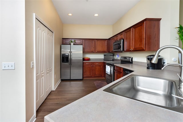 kitchen with appliances with stainless steel finishes, dark wood-type flooring, and sink