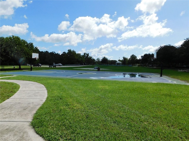 view of property's community with basketball hoop and a yard