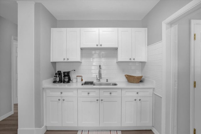 kitchen featuring decorative backsplash, sink, hardwood / wood-style flooring, and white cabinets