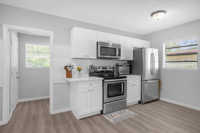 kitchen featuring appliances with stainless steel finishes, white cabinetry, a healthy amount of sunlight, and light wood-type flooring