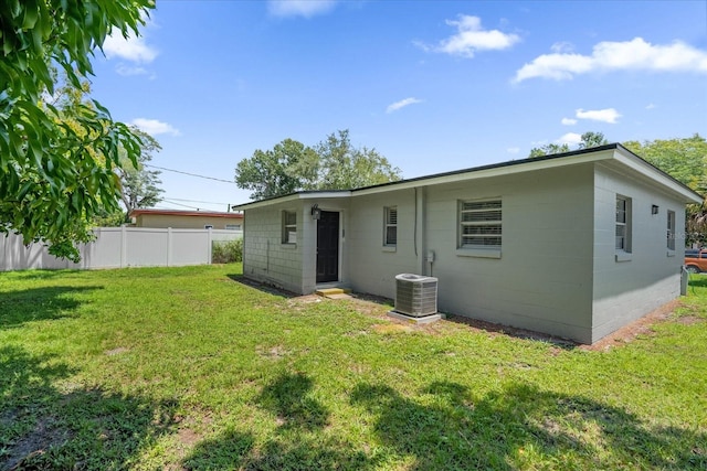 rear view of property with central AC and a lawn