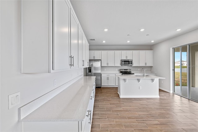 kitchen featuring appliances with stainless steel finishes, sink, a center island with sink, and white cabinets