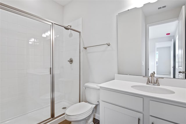 bathroom featuring a shower with door, vanity, and toilet