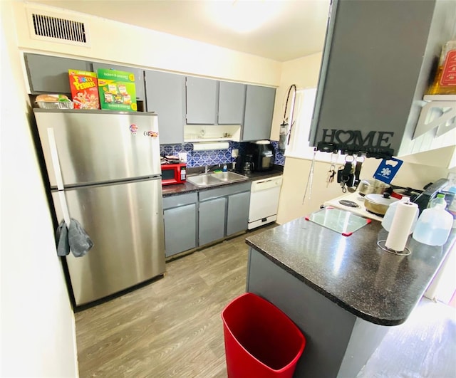 kitchen with light hardwood / wood-style flooring, white dishwasher, stainless steel refrigerator, gray cabinetry, and sink