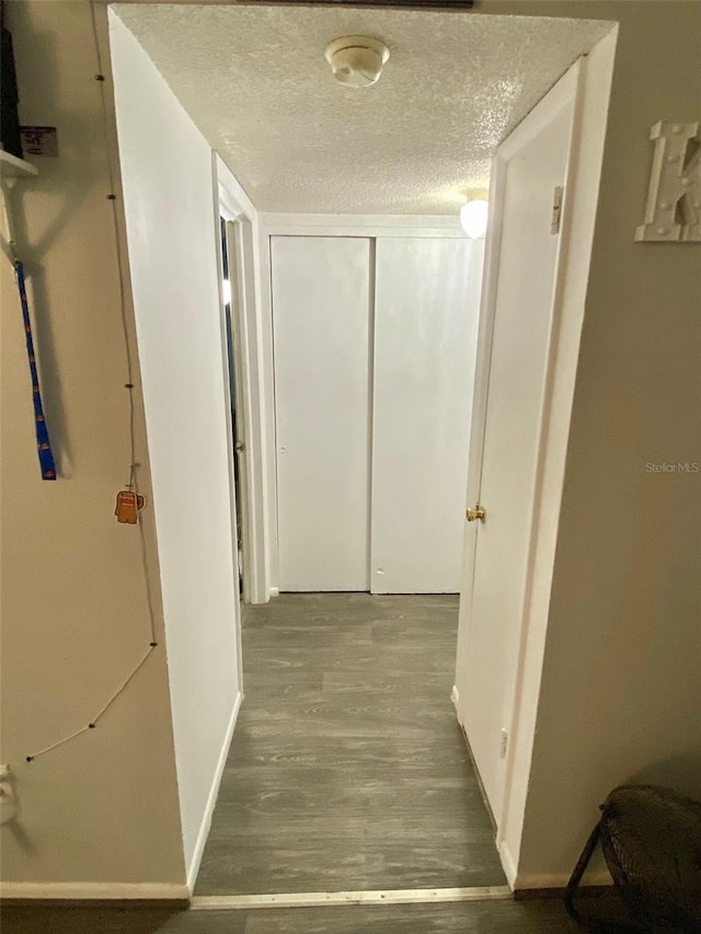 corridor featuring wood-type flooring and a textured ceiling