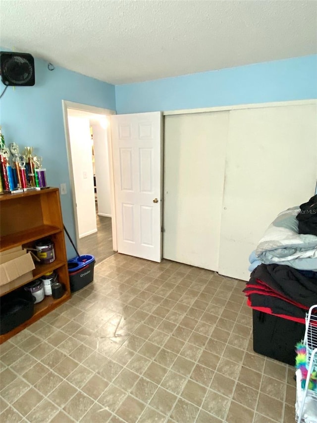 tiled bedroom featuring a textured ceiling and a closet