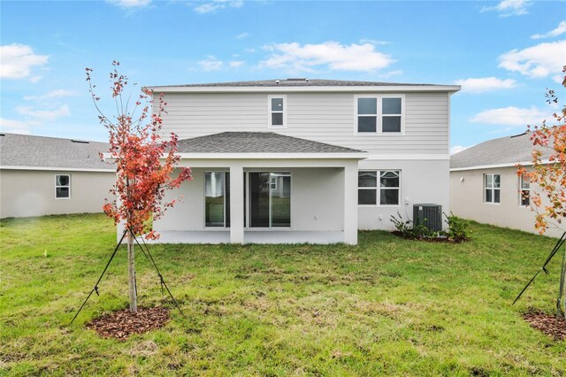 back of house featuring cooling unit, a patio area, and a lawn