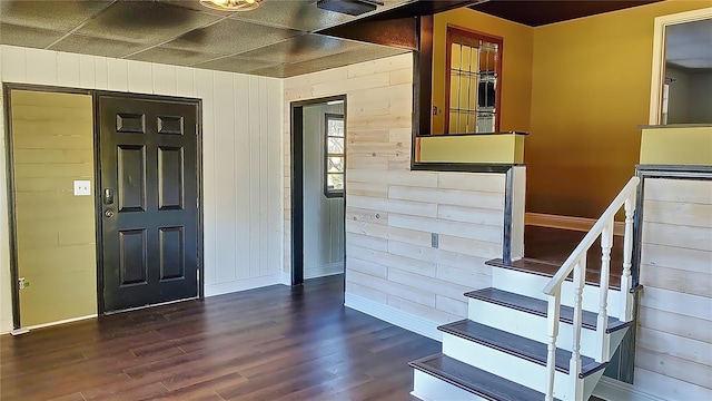 foyer entrance with dark wood-type flooring and wood walls