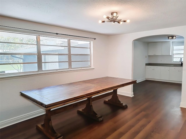 dining area featuring sink, dark hardwood / wood-style flooring, a chandelier, and a textured ceiling