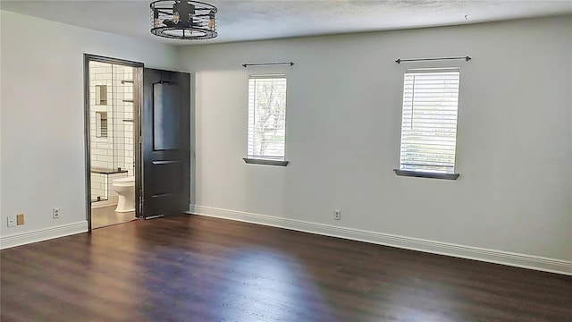 unfurnished bedroom with ensuite bath and dark hardwood / wood-style flooring