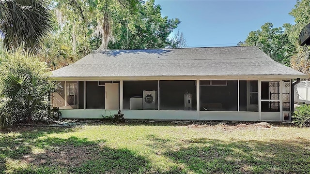 back of property featuring roof with shingles, a sunroom, and a yard
