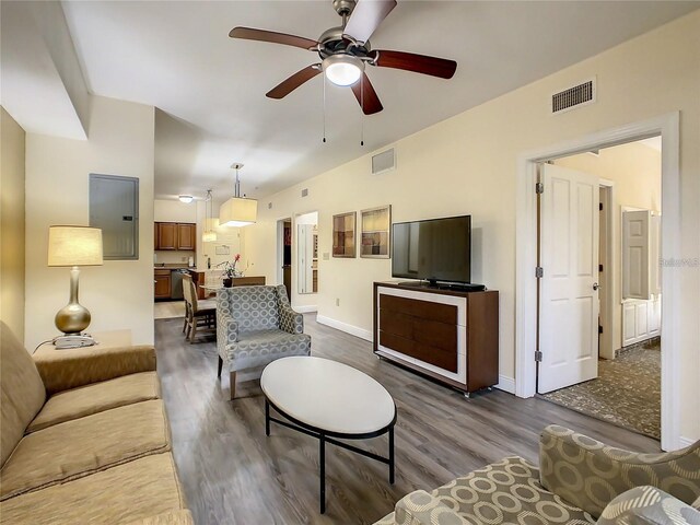 living room with electric panel, dark wood-type flooring, and ceiling fan