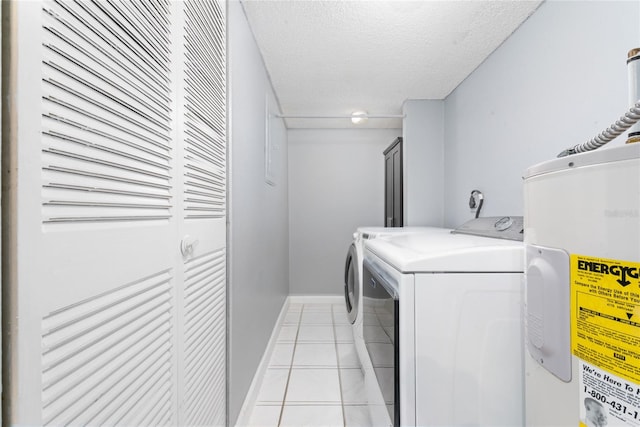 laundry area with water heater, light tile patterned floors, a textured ceiling, and washing machine and clothes dryer