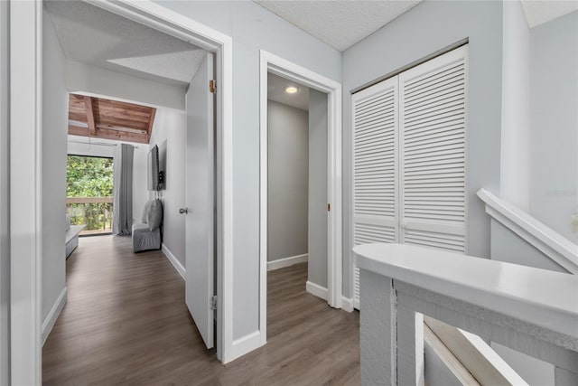 corridor featuring hardwood / wood-style floors, a textured ceiling, and beam ceiling