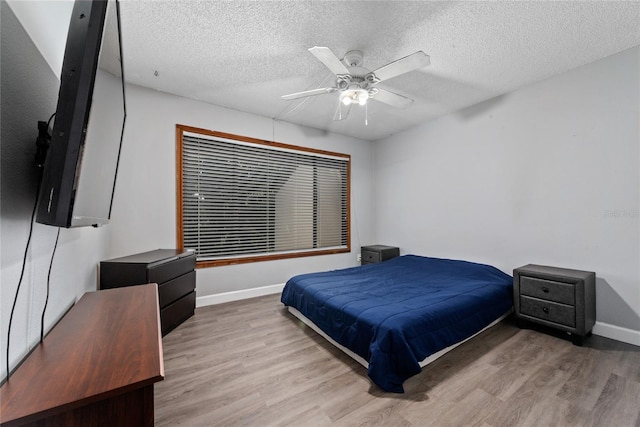 bedroom with a textured ceiling, light wood-type flooring, and ceiling fan