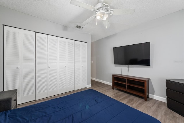 unfurnished bedroom with ceiling fan, a textured ceiling, light hardwood / wood-style floors, and a closet