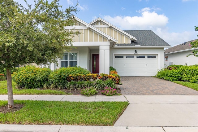 craftsman house featuring a garage, roof with shingles, decorative driveway, and board and batten siding