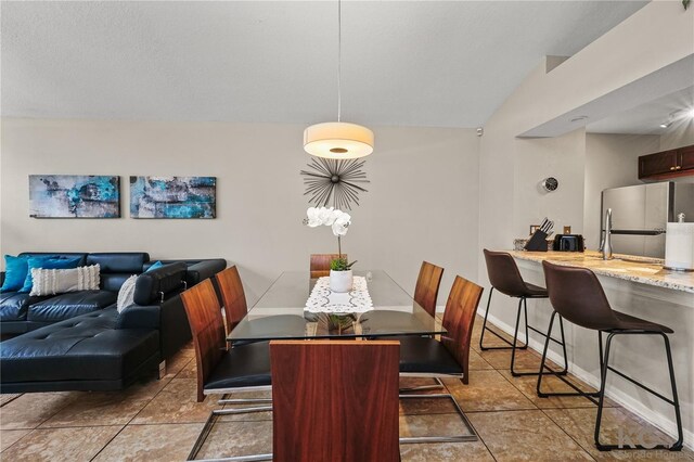 dining space with light tile patterned flooring and lofted ceiling