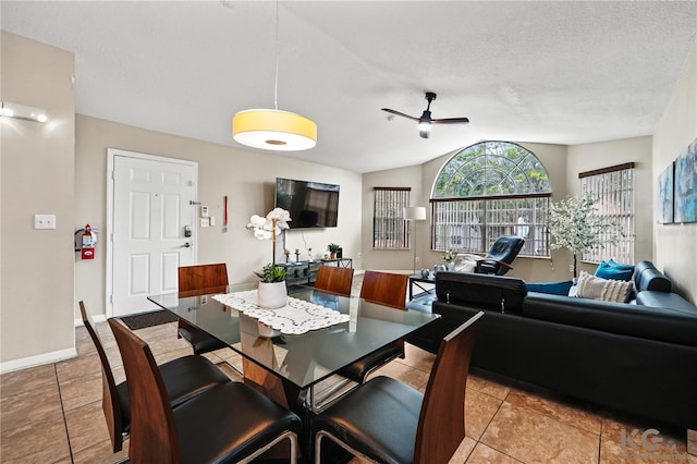 tiled dining area with ceiling fan, vaulted ceiling, and a textured ceiling