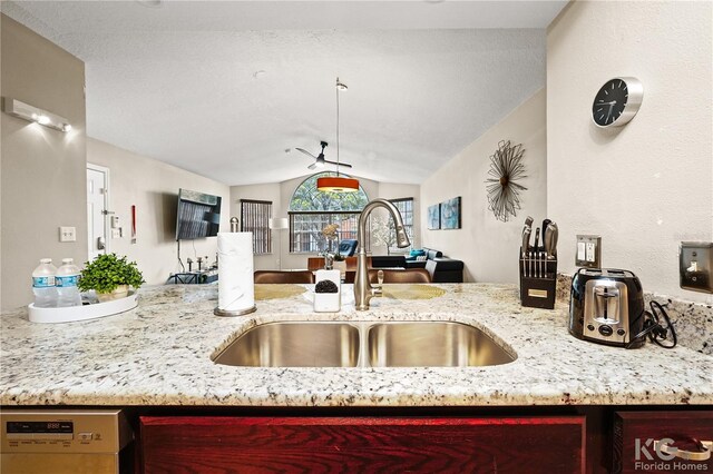 kitchen featuring vaulted ceiling, light stone countertops, ceiling fan, white dishwasher, and sink