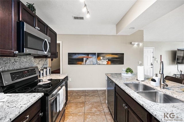 kitchen with stainless steel appliances, dark brown cabinetry, light tile patterned floors, and sink