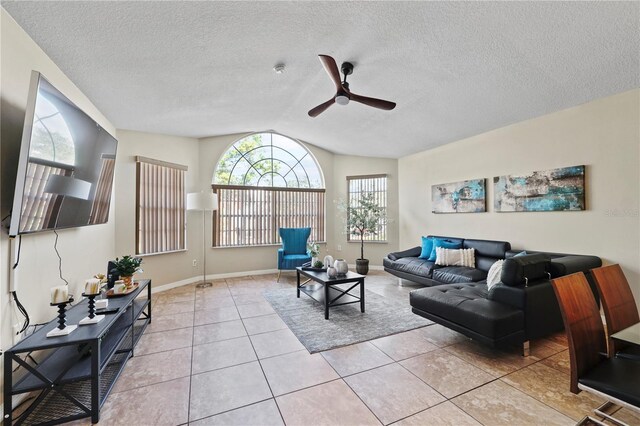 tiled living room with ceiling fan, vaulted ceiling, and a textured ceiling