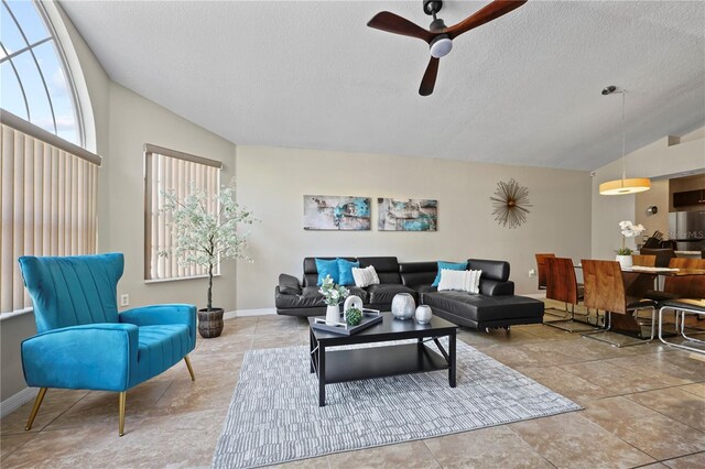 living room featuring tile patterned floors, a textured ceiling, ceiling fan, and vaulted ceiling