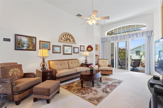 carpeted living room featuring ceiling fan and a high ceiling