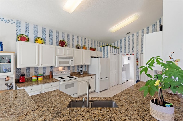 kitchen featuring sink, white appliances, white cabinets, and dark stone counters