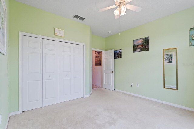 unfurnished bedroom with ceiling fan, a closet, and carpet floors