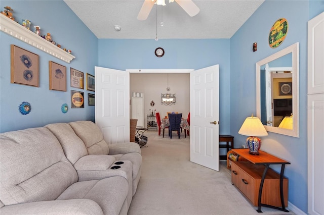 living room featuring light carpet, ceiling fan with notable chandelier, and a textured ceiling