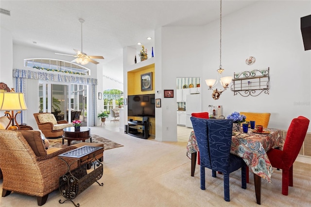 dining area featuring ceiling fan with notable chandelier, a high ceiling, and light colored carpet