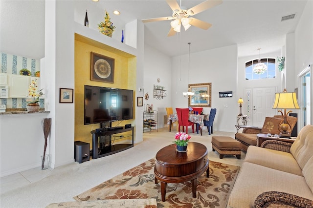 carpeted living room featuring a towering ceiling and ceiling fan with notable chandelier