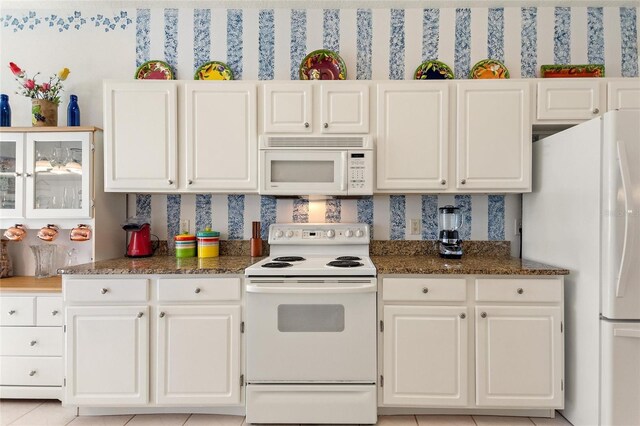 kitchen with light tile patterned floors, white appliances, and white cabinetry