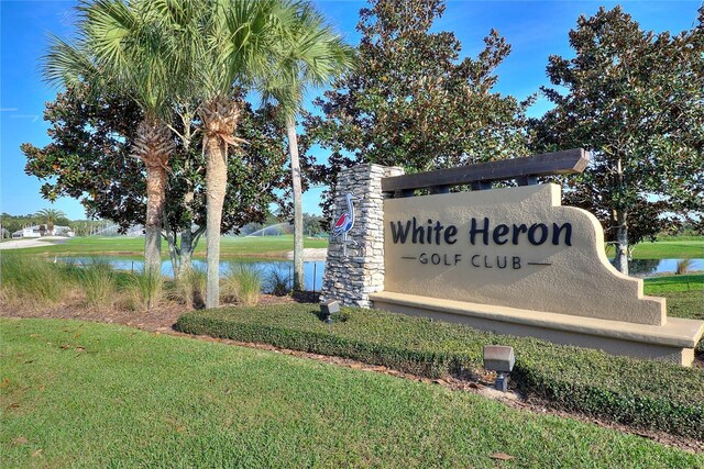 community sign with a lawn and a water view