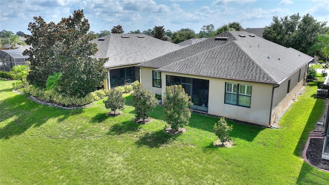 rear view of property featuring a yard, a shingled roof, and stucco siding