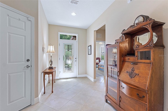 entryway featuring light tile patterned floors, baseboards, visible vents, and a textured ceiling