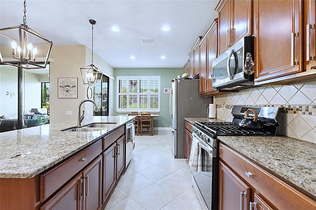 kitchen with visible vents, appliances with stainless steel finishes, hanging light fixtures, a kitchen island with sink, and a sink