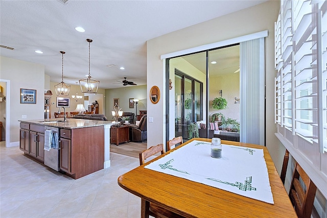 kitchen with light tile patterned flooring, a sink, open floor plan, an island with sink, and pendant lighting