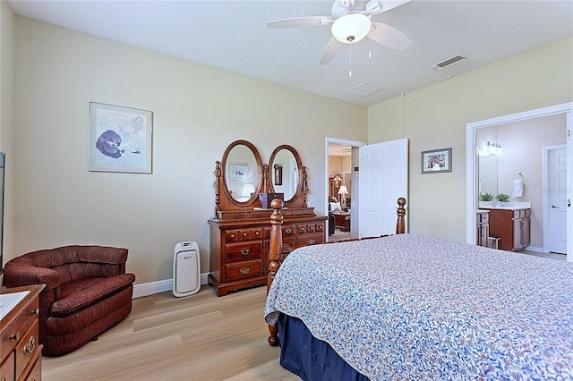 bedroom featuring light wood finished floors, visible vents, baseboards, ensuite bath, and ceiling fan