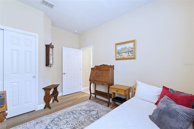 bedroom featuring baseboards, visible vents, and light wood finished floors