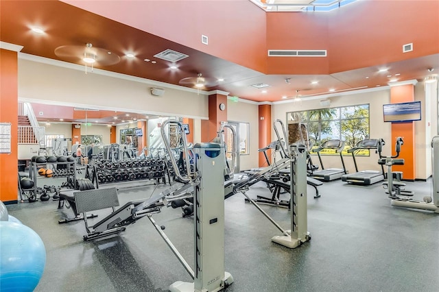 exercise room with a high ceiling, visible vents, and crown molding