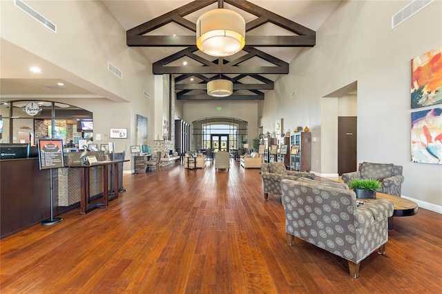 entrance foyer with wood finished floors, visible vents, a towering ceiling, baseboards, and beamed ceiling