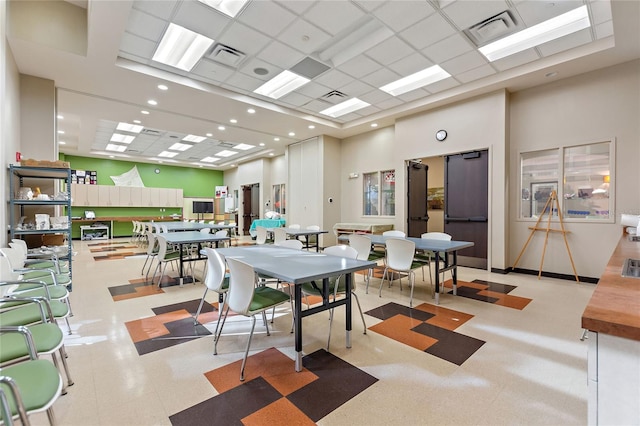 dining space featuring a high ceiling, a paneled ceiling, and visible vents