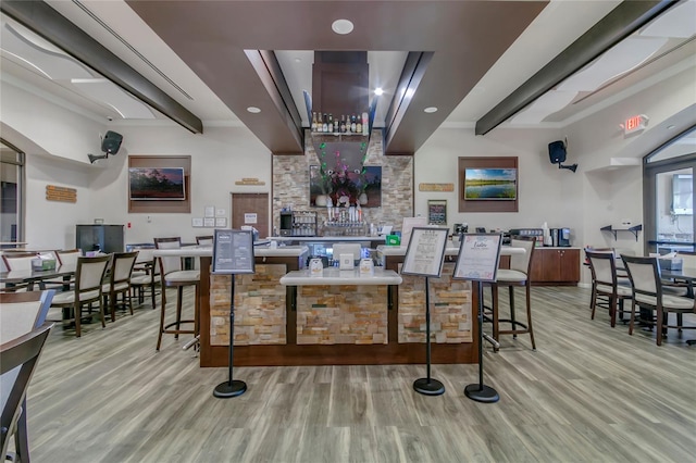 bar with light wood-style floors and beam ceiling