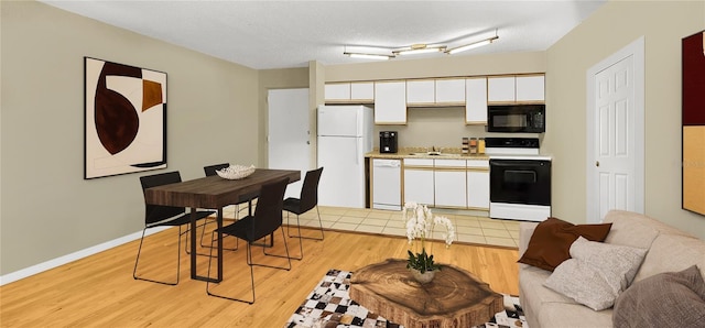 kitchen with white appliances, light wood-style floors, white cabinets, and a sink