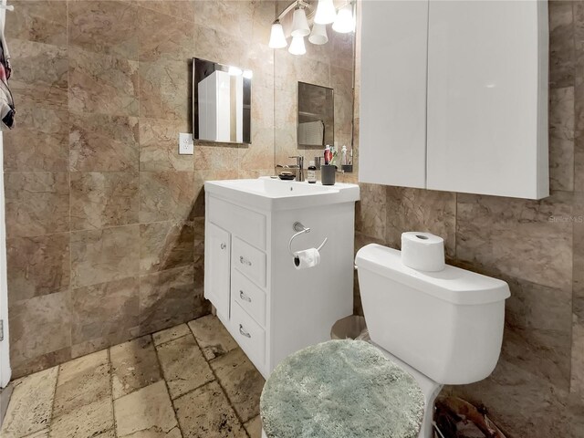 bathroom with tile walls, vanity, tile patterned flooring, and toilet