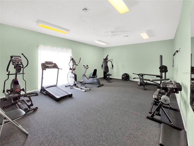 gym with a ceiling fan, visible vents, a textured ceiling, and baseboards