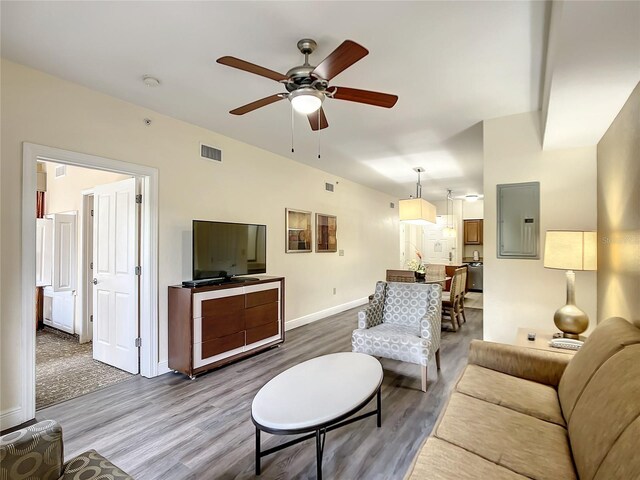 living room with electric panel, hardwood / wood-style flooring, and ceiling fan